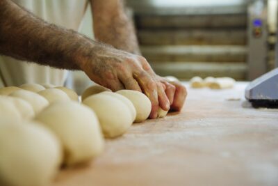 balls of uncooked dough being shaped by a pair of hands