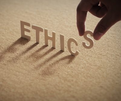 The letters of the word "Ethics" standing on a san-colored background as the final "S" is placed