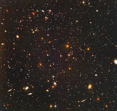 image from the Hubble Space Telescope showing thousands of galaxies (colored dots). Even the tiny dots are whole galaxies.