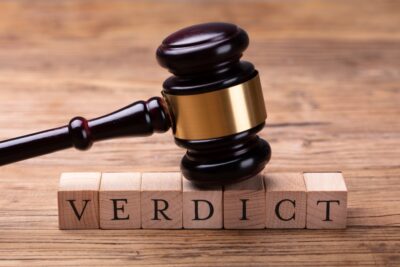 judge's gavel resting on wooden blocks with letters spelling out the word "Verdict"