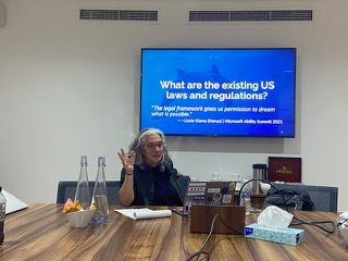 Lainey presenting in a conference room in front of a slide that reads 'What are the Existing US Digital Accessibility Laws and Regulations