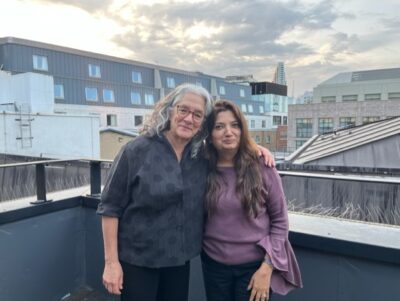 Lainey Feingold and Shilpi Kapoor smiling on a London rooftop