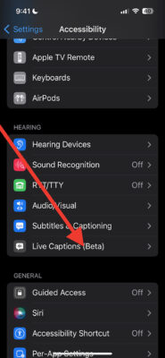 screenshot of the Apple iPhone settings screen showing options available to people with hearing disabilities. There is a red arrow pointed at the last option which reads "Live Captions (Beta)