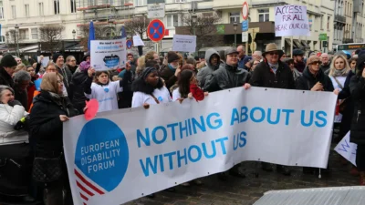 protest with advocates in the front holding a banner saying "Nothing about us without us" and the logo of the european Disability Forum