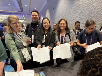 Smiling reader who just purchased the book and have copies opened to where authors signed